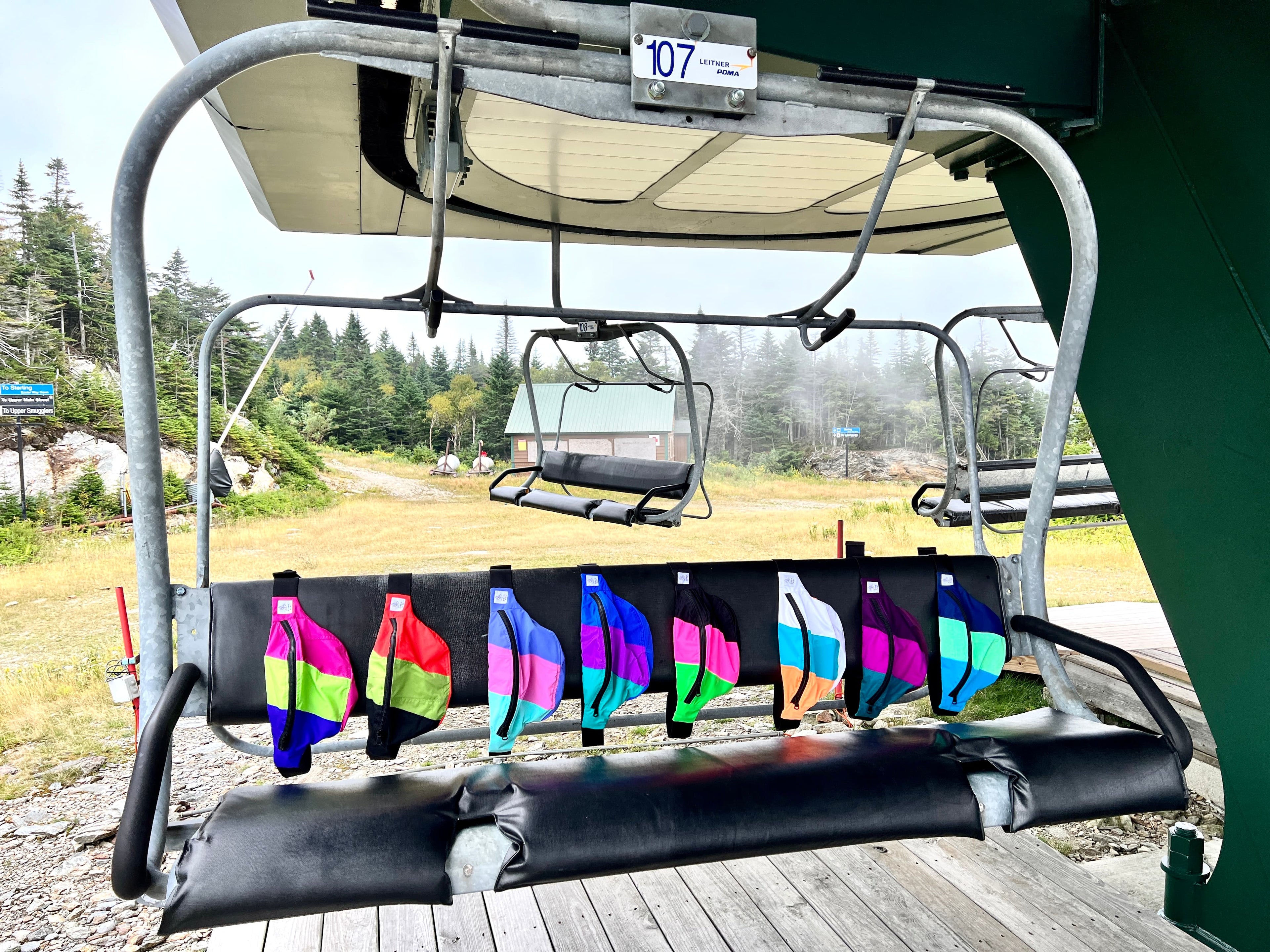 Color fanny packs hanging on a ski chair lift 