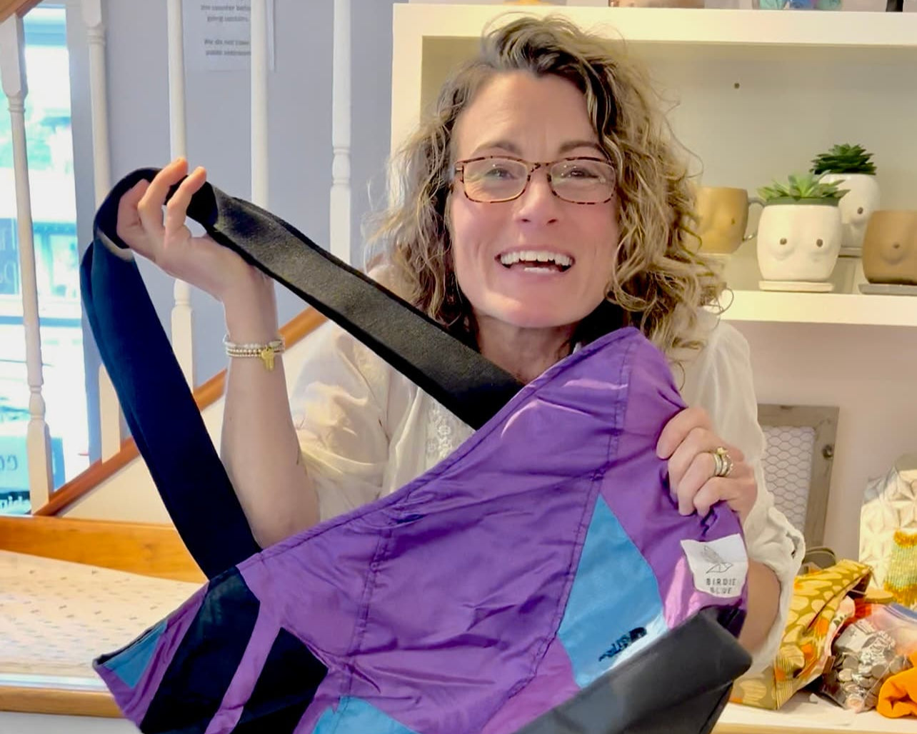 Woman holding a purple baby carrier in a store setting
