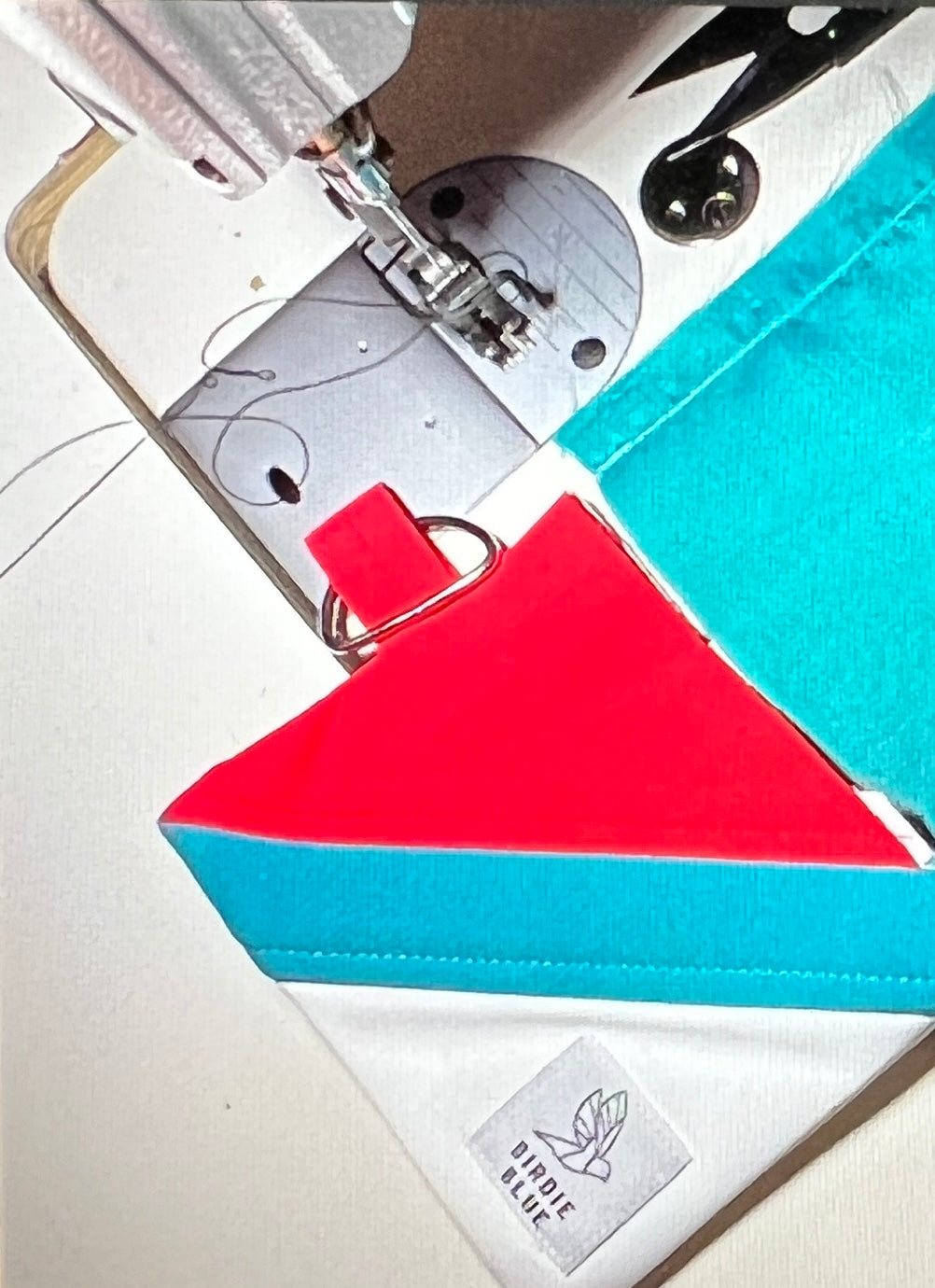 Colorful zipper wallet next to sewing machine made from old ski and snowboard clothing