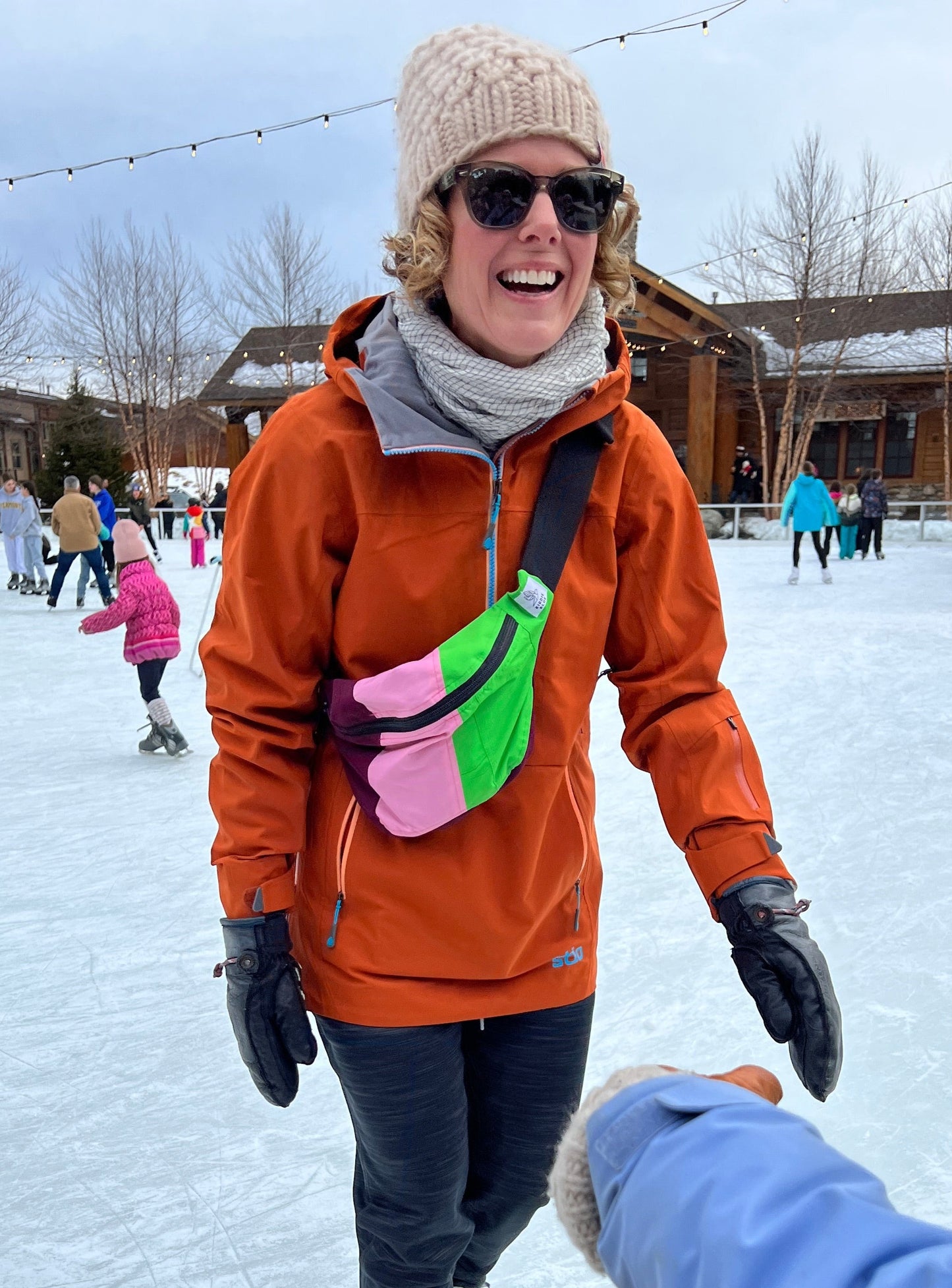 woman smiling while ice skating with a bright colored fanny pack