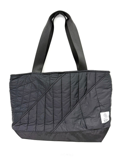 A black quilted tote bag with diagonal stitched paneling, dual shoulder straps, and a small white brand tag on the lower right side, shown against a plain white background.
